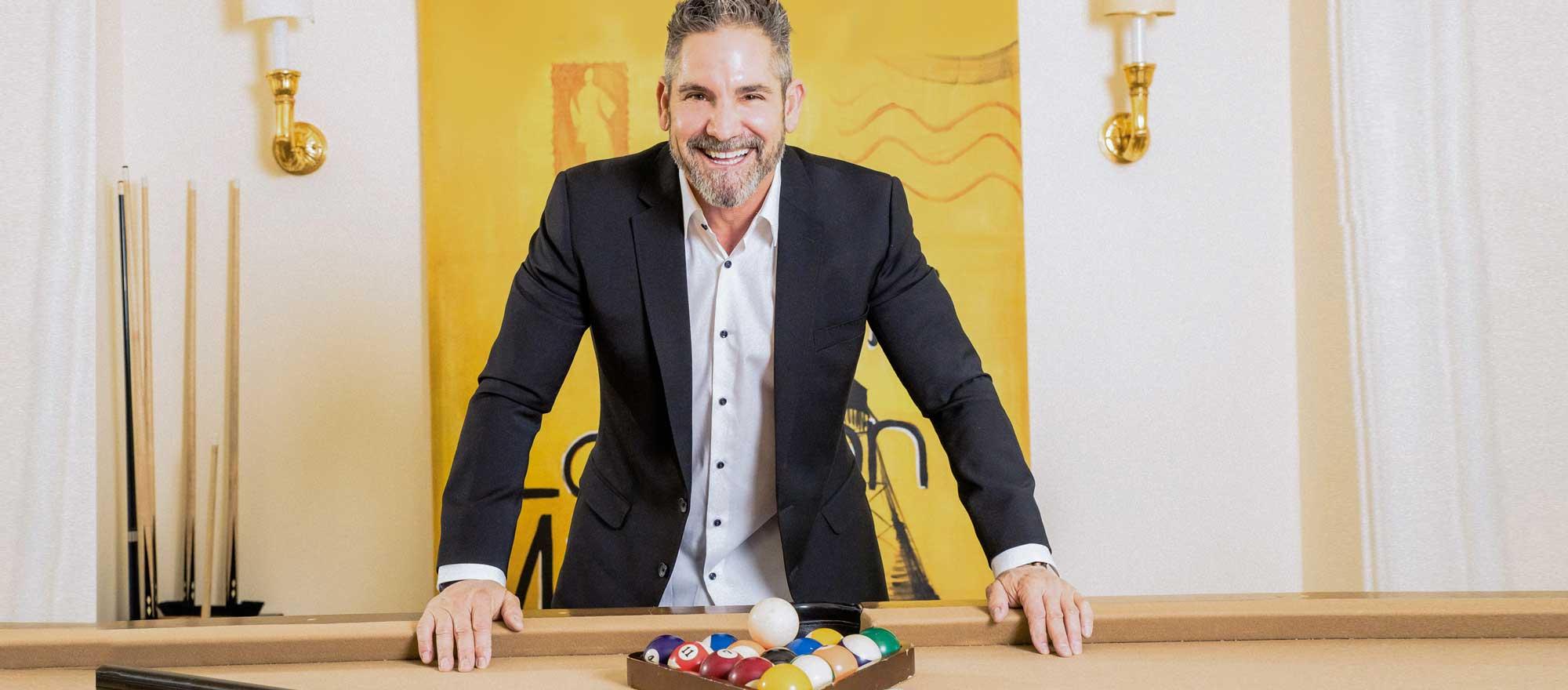 Grant Cardone smiling and leaning over a pool table'