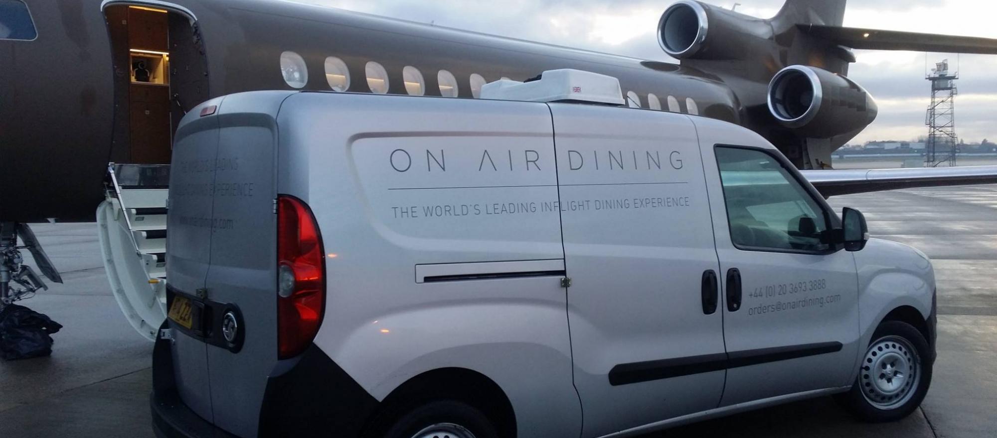 On Air Dining catering delivery van on airport ramp next to a Falcon business jet