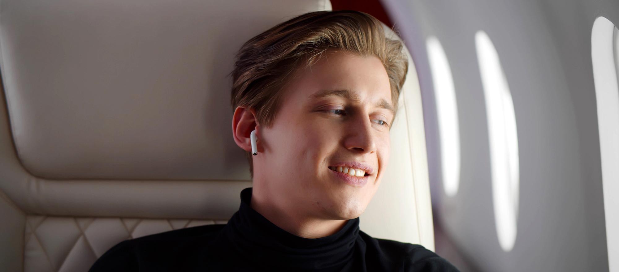 Young business jet passenger with earbuds on