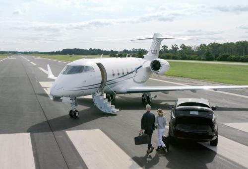 Business jet on runway with people about to board after leaving their car