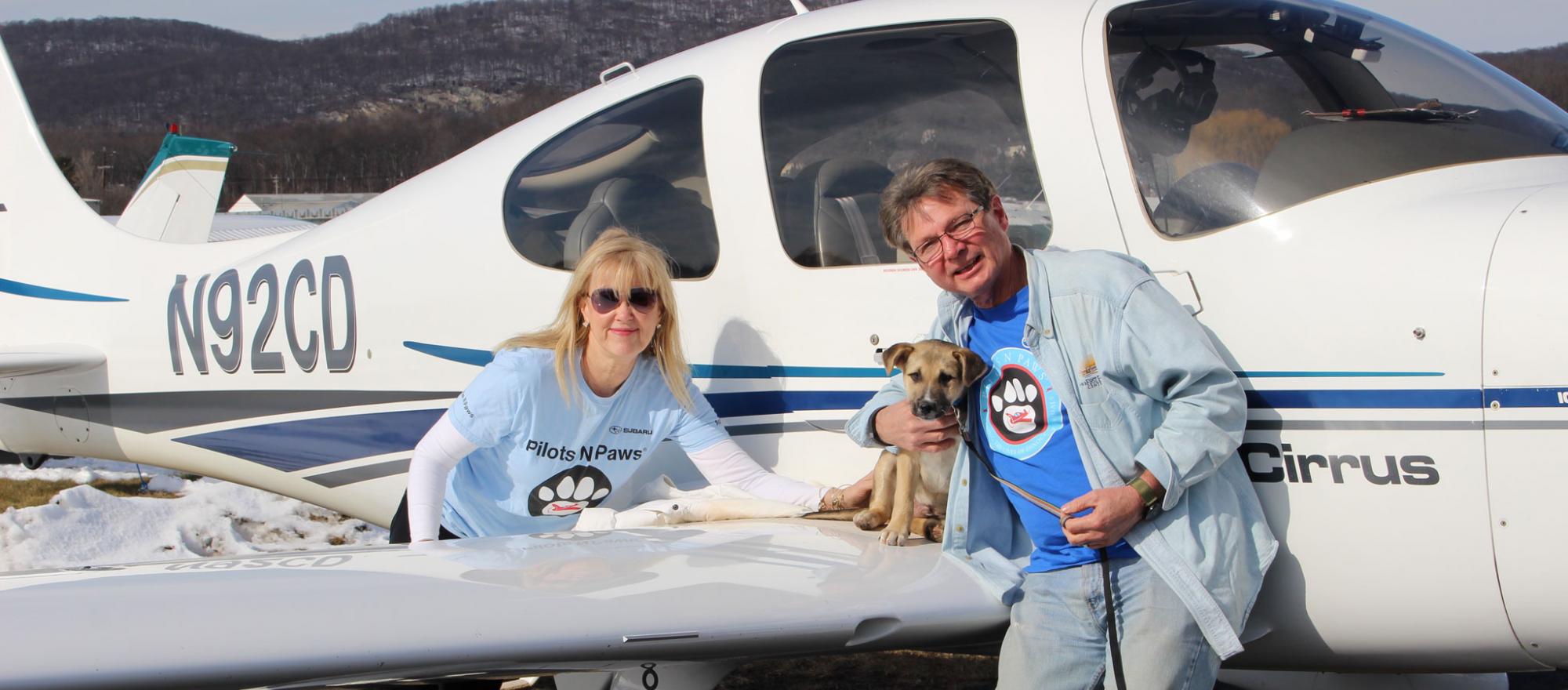 Pilots N Paws volunteers with rescue puppy on wing of Cirrus Aircraft following a rescue flight
