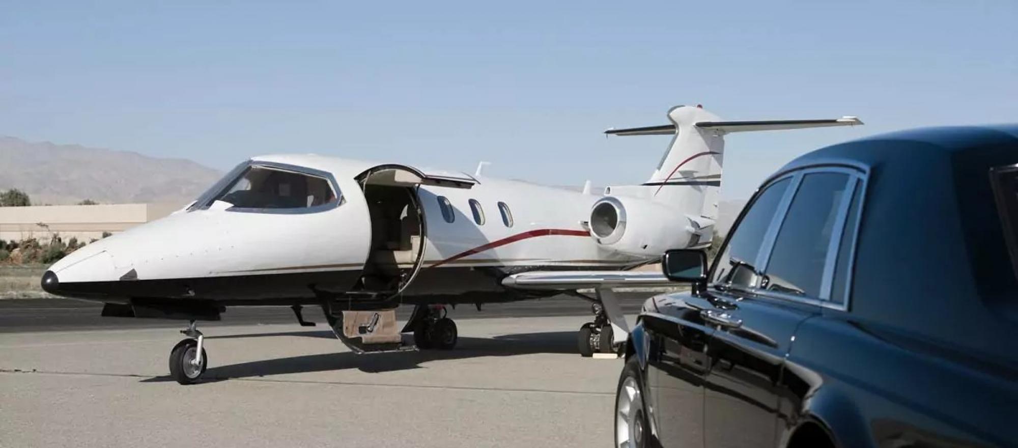 Business jet with door open greeted by courtesy car on airport ramp