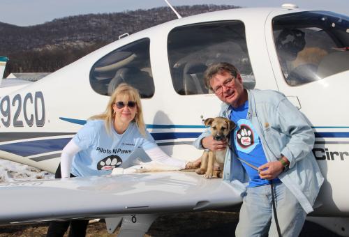 Pilots N Paws volunteers with rescue puppy on wing of Cirrus Aircraft following a rescue flight