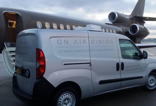 On Air Dining catering delivery van on airport ramp next to a Falcon business jet